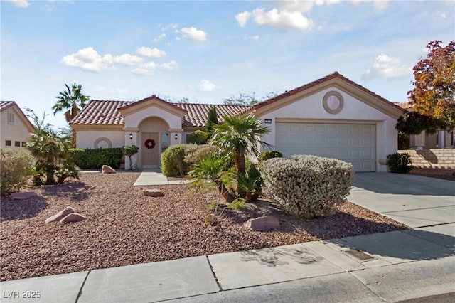 mediterranean / spanish home featuring a garage, a tile roof, concrete driveway, and stucco siding