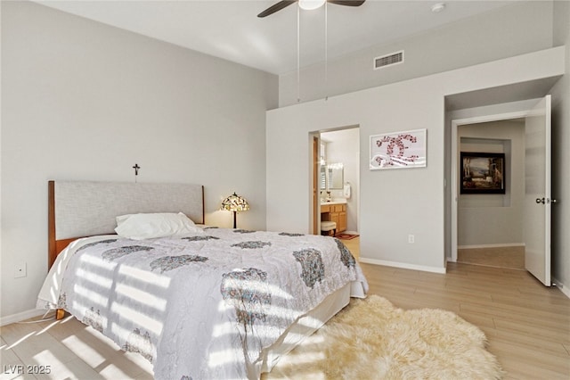 bedroom featuring ceiling fan, visible vents, baseboards, light wood-type flooring, and ensuite bath