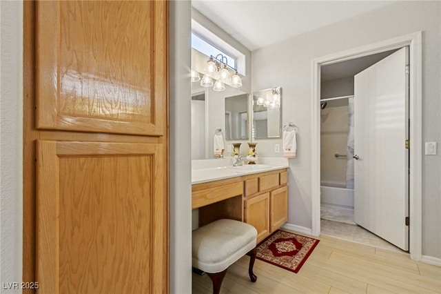 full bath with bathtub / shower combination, vanity, baseboards, and wood finished floors