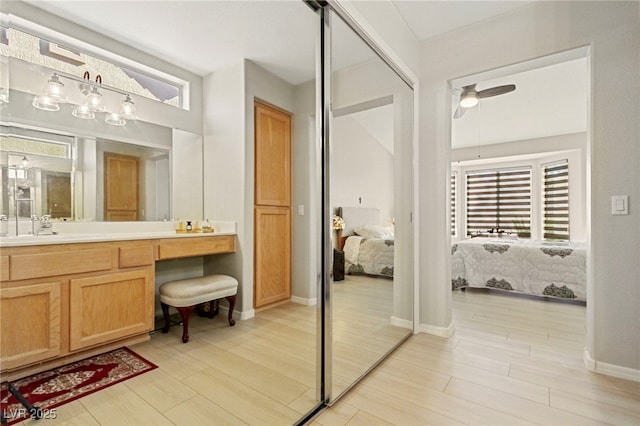 full bathroom with ceiling fan, wood finished floors, vanity, baseboards, and ensuite bath