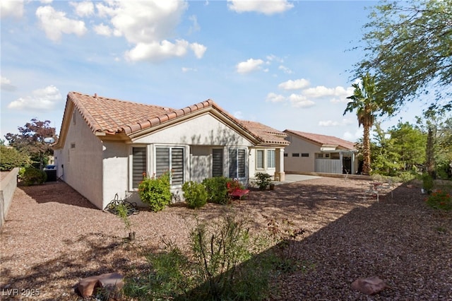 rear view of property featuring central air condition unit, a tile roof, fence, and stucco siding