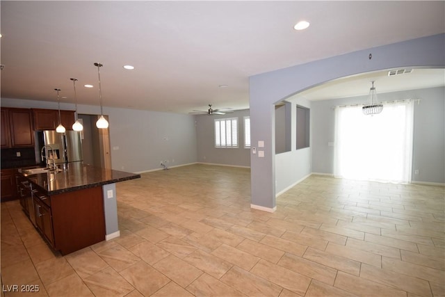 kitchen with ceiling fan with notable chandelier, a sink, visible vents, open floor plan, and stainless steel refrigerator with ice dispenser