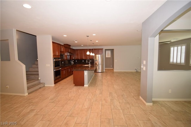 kitchen featuring recessed lighting, a sink, baseboards, open floor plan, and appliances with stainless steel finishes