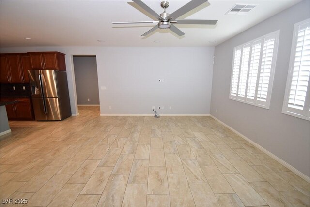 spare room with light wood-type flooring, baseboards, visible vents, and a ceiling fan