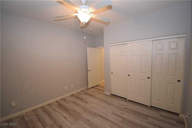 unfurnished bedroom featuring light wood-style floors, a closet, baseboards, and a ceiling fan