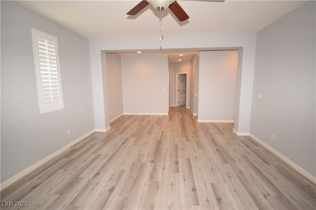 empty room with a ceiling fan, light wood-type flooring, and baseboards