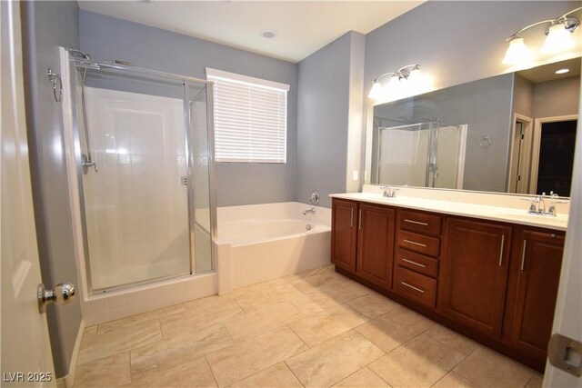 bathroom with double vanity, a garden tub, a shower stall, and a sink