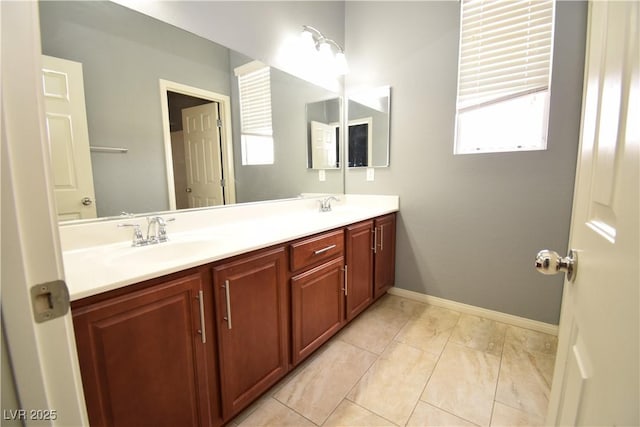 bathroom with double vanity, tile patterned floors, a sink, and baseboards