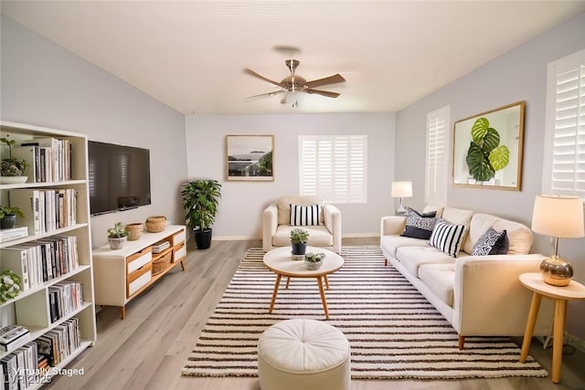living room featuring light wood-style floors, ceiling fan, and baseboards
