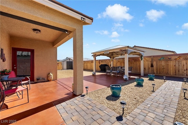 view of patio with a gazebo, a storage unit, an outbuilding, and a fenced backyard