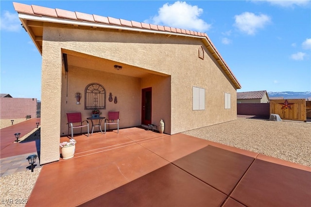 back of property featuring stucco siding, fence, and a patio area