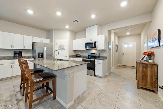 kitchen featuring visible vents, a breakfast bar, recessed lighting, appliances with stainless steel finishes, and a sink