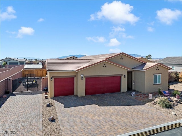 view of front of house featuring fence, stucco siding, decorative driveway, a garage, and a gate