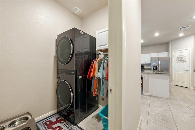 laundry area with stacked washer / dryer, visible vents, baseboards, light tile patterned floors, and recessed lighting