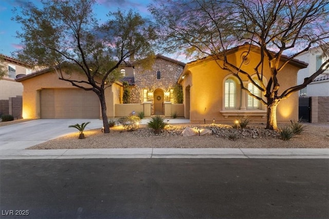 mediterranean / spanish-style house featuring driveway, stone siding, a fenced front yard, an attached garage, and stucco siding