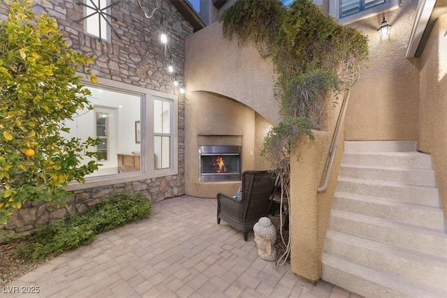 exterior space with a warm lit fireplace and brick floor