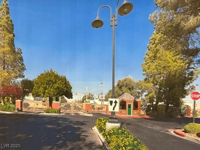 view of street with traffic signs, a gate, curbs, and a gated entry