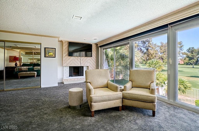 living area featuring a fireplace, visible vents, ornamental molding, carpet flooring, and a textured ceiling