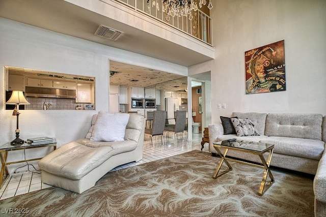 living room featuring a towering ceiling, visible vents, and tile patterned floors