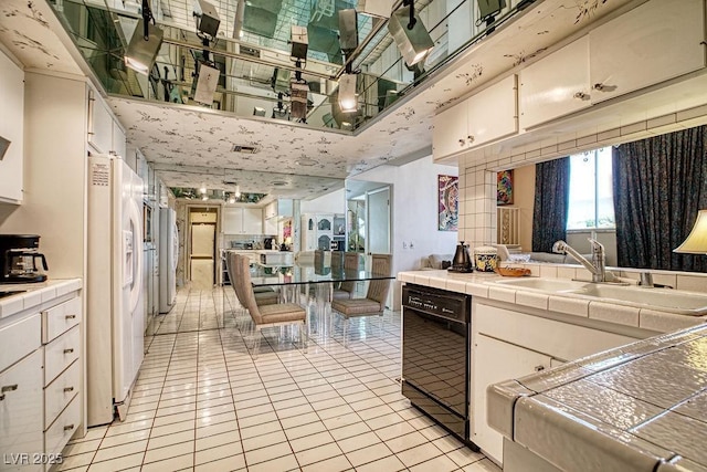 kitchen featuring light tile patterned floors, black dishwasher, tile countertops, white fridge with ice dispenser, and white cabinetry