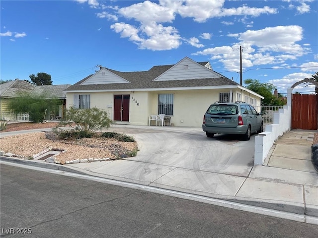 ranch-style house featuring roof with shingles, fence, driveway, and stucco siding