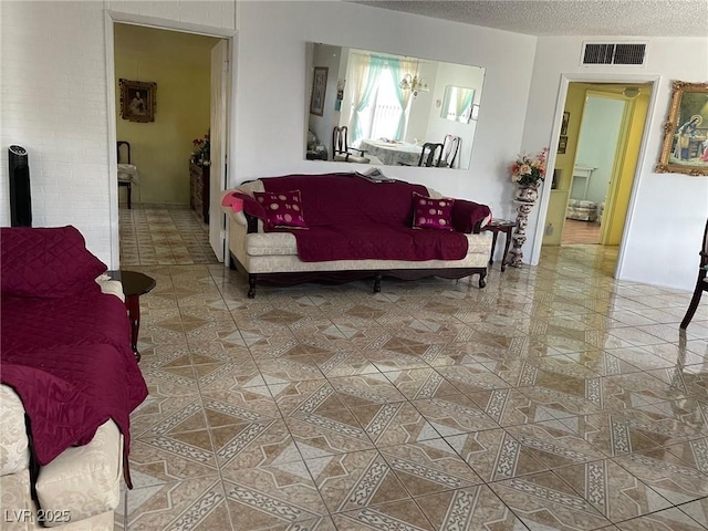 tiled living room featuring visible vents and a textured ceiling