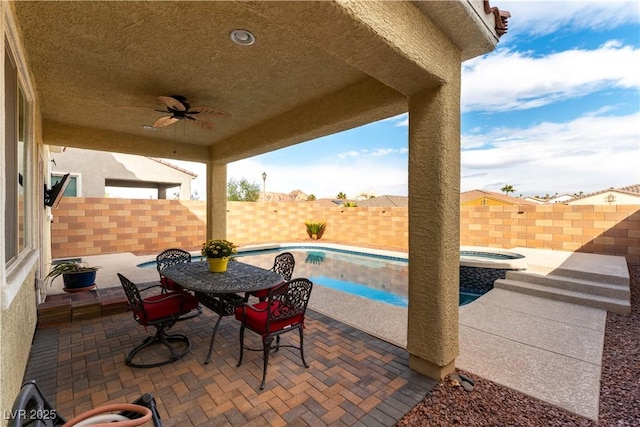 view of patio / terrace with ceiling fan, outdoor dining space, a fenced backyard, and a pool with connected hot tub