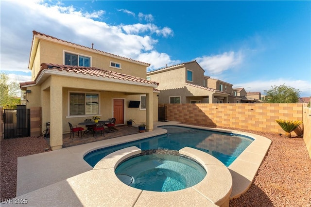 back of property featuring a patio, a fenced backyard, a pool with connected hot tub, a tiled roof, and stucco siding