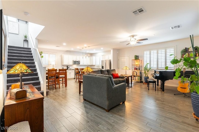 living area featuring a healthy amount of sunlight, stairway, visible vents, and wood finished floors