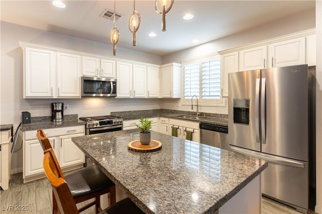 kitchen with white cabinets, visible vents, stainless steel appliances, and a sink