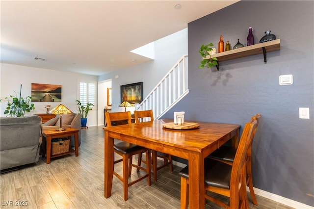 dining room with visible vents, stairs, light wood-style flooring, and baseboards