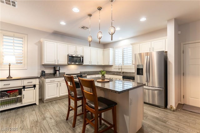 kitchen featuring stainless steel appliances, light wood-style floors, visible vents, and a sink