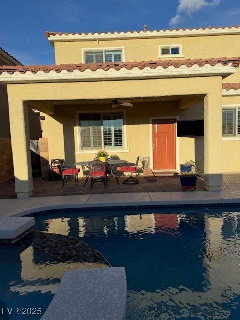 back of house with a patio area, an outdoor pool, and a tiled roof