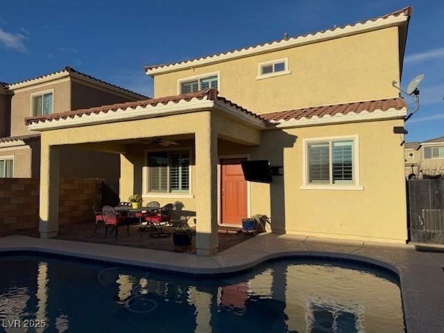 back of house with an outdoor pool, a patio area, fence, and stucco siding