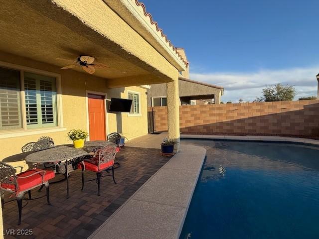 view of pool featuring a patio, outdoor dining space, a fenced backyard, and a ceiling fan