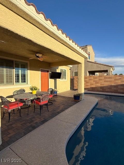 view of patio / terrace featuring ceiling fan, fence, and an outdoor pool