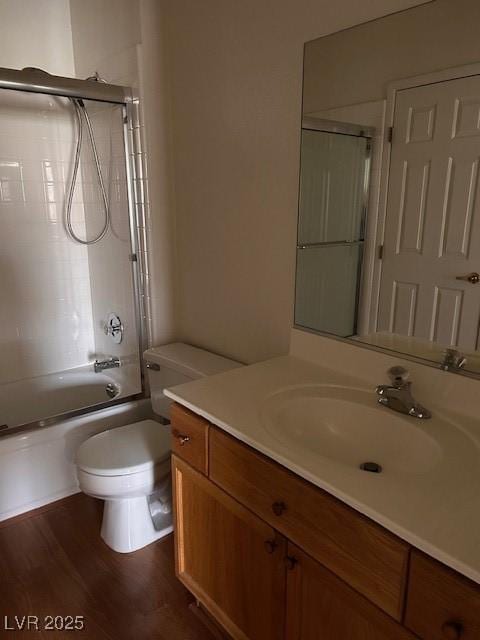 full bathroom featuring combined bath / shower with glass door, vanity, toilet, and wood finished floors