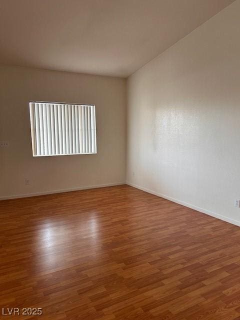 spare room featuring baseboards and wood finished floors