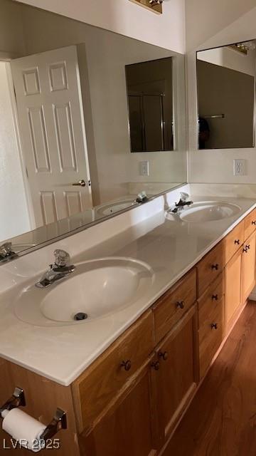 full bathroom with double vanity, a sink, and wood finished floors