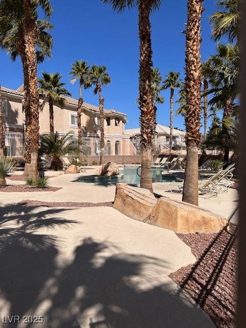 view of front of home featuring an outdoor pool, stucco siding, a patio, and fence