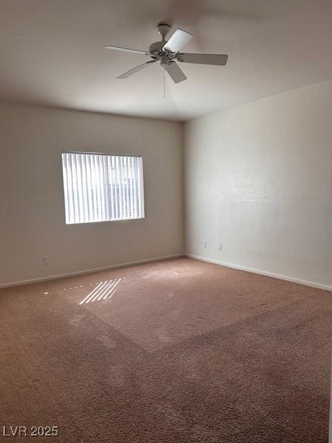 carpeted spare room featuring a ceiling fan and baseboards