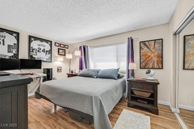 bedroom with a textured ceiling, baseboards, and wood finished floors