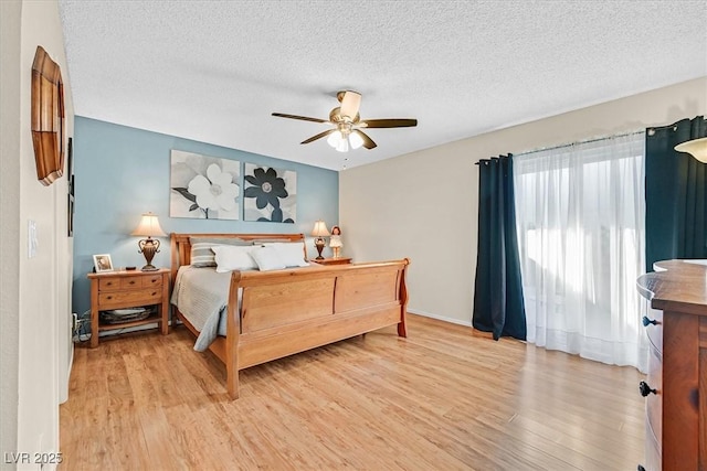 bedroom featuring light wood-style flooring, a textured ceiling, and a ceiling fan