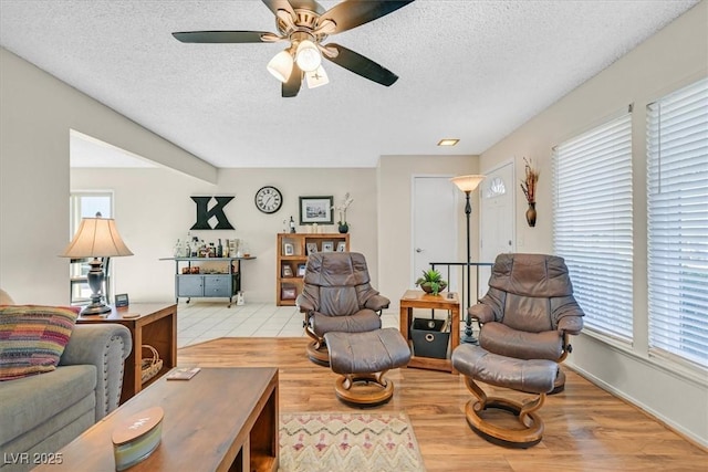 living room featuring ceiling fan, a textured ceiling, and wood finished floors