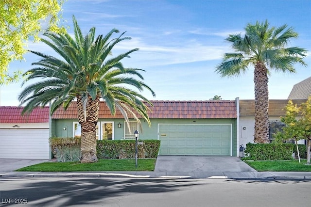 view of front of house featuring a garage, mansard roof, concrete driveway, and stucco siding