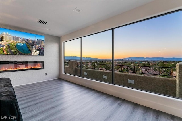 interior space featuring a mountain view, wood finished floors, a glass covered fireplace, and visible vents