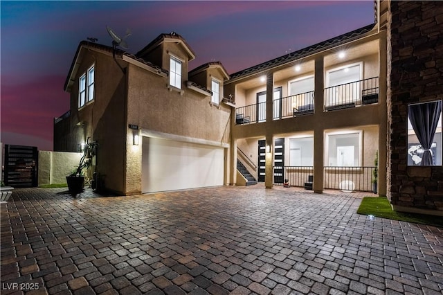 view of front of home featuring stairs, decorative driveway, and stucco siding