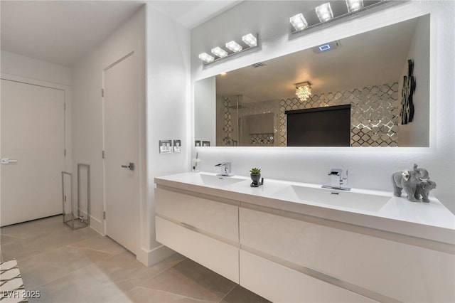 bathroom with double vanity, tile patterned flooring, a tile shower, and a sink