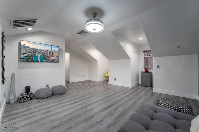 additional living space featuring vaulted ceiling, wood finished floors, visible vents, and baseboards