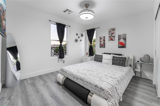 bedroom with baseboards, visible vents, and wood finished floors